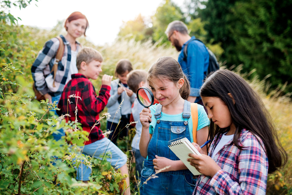 favoriser-autonomie Enfants avec leurs parents dans la forêt qui font un jeu de piste