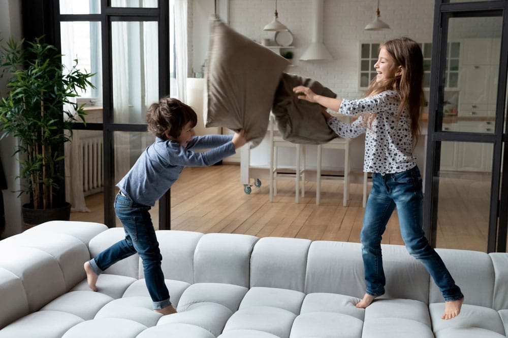 fratrie enfants qui font une bataille avec des coussins