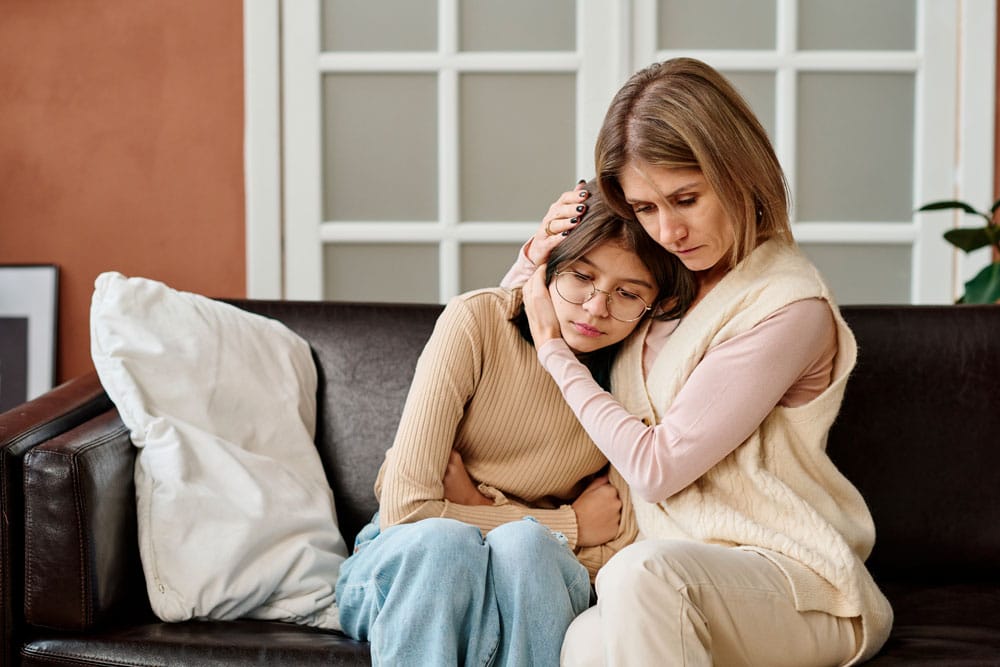 gestion-colere Maman qui réconforte son adolescente dans leur salon.