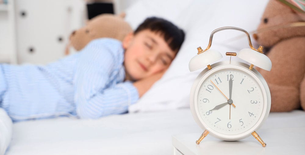 gestion-du-sommeil Enfant qui dort avec un réveil